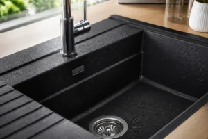 Évier en granit composite noir mat encastré dans un plan de travail bois, vue rapprochée