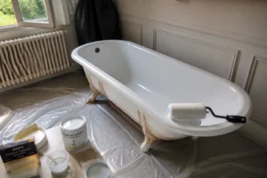 Baignoire en fonte émaillée en cours de peinture avec rouleau mousse et pot d'époxy bicomposante