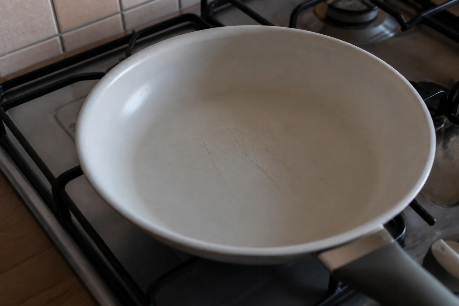 Poêle en céramique posée sur une plaque de cuisson avec revêtement usé visible